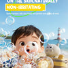 A child is surrounded by bubbles and a camera-shaped automatic bubble machine with lights on a sandy beach.