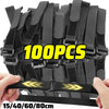 A hand is holding a bundle of black reusable nylon cable ties with adjustable hook and loop fasteners.