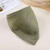 A soft olive green cotton baby bib is shown lying on a light surface.