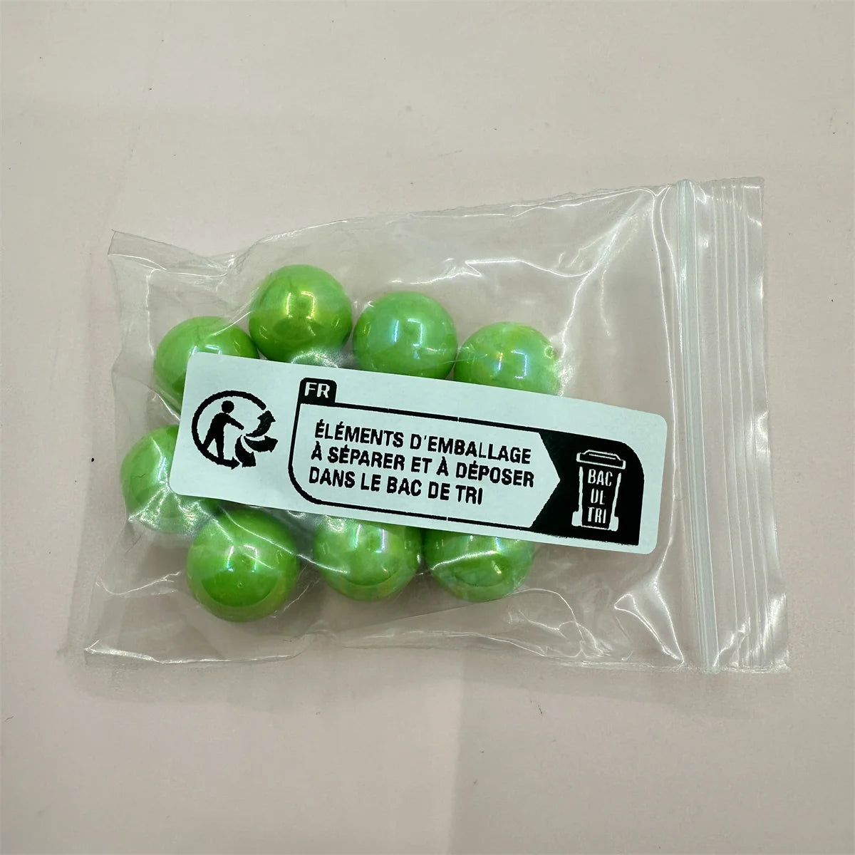 A clear plastic bag contains several bright green acrylic beads for jewelry making with an instruction label.