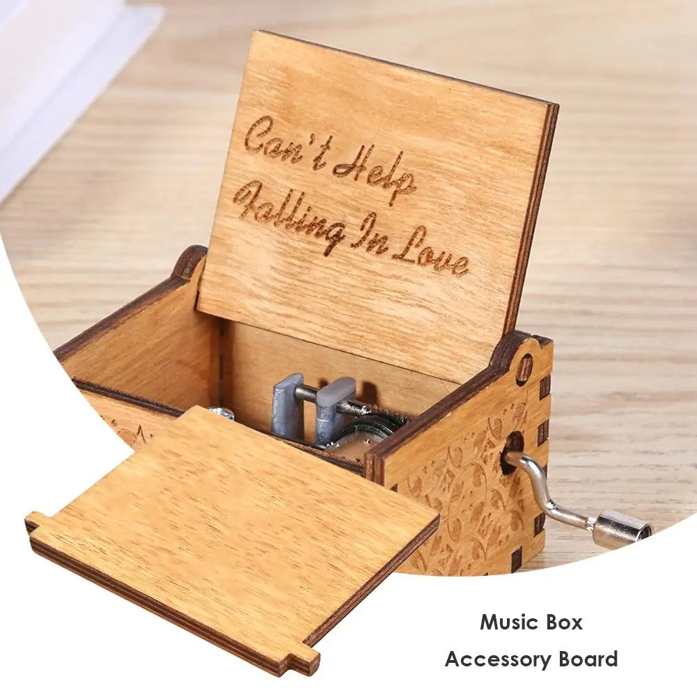 A hand-cranked wooden music box with an accessory board and a lid, made of light wood.