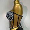 A gold mannequin displays a sparkly two-piece party outfit with a see-through top and black detailing.