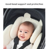 A baby is seated in a white and black stroller seat cushion designed for good head support and protection.