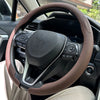A close-up view of a brown leather steering wheel cover installed on a car's steering wheel.