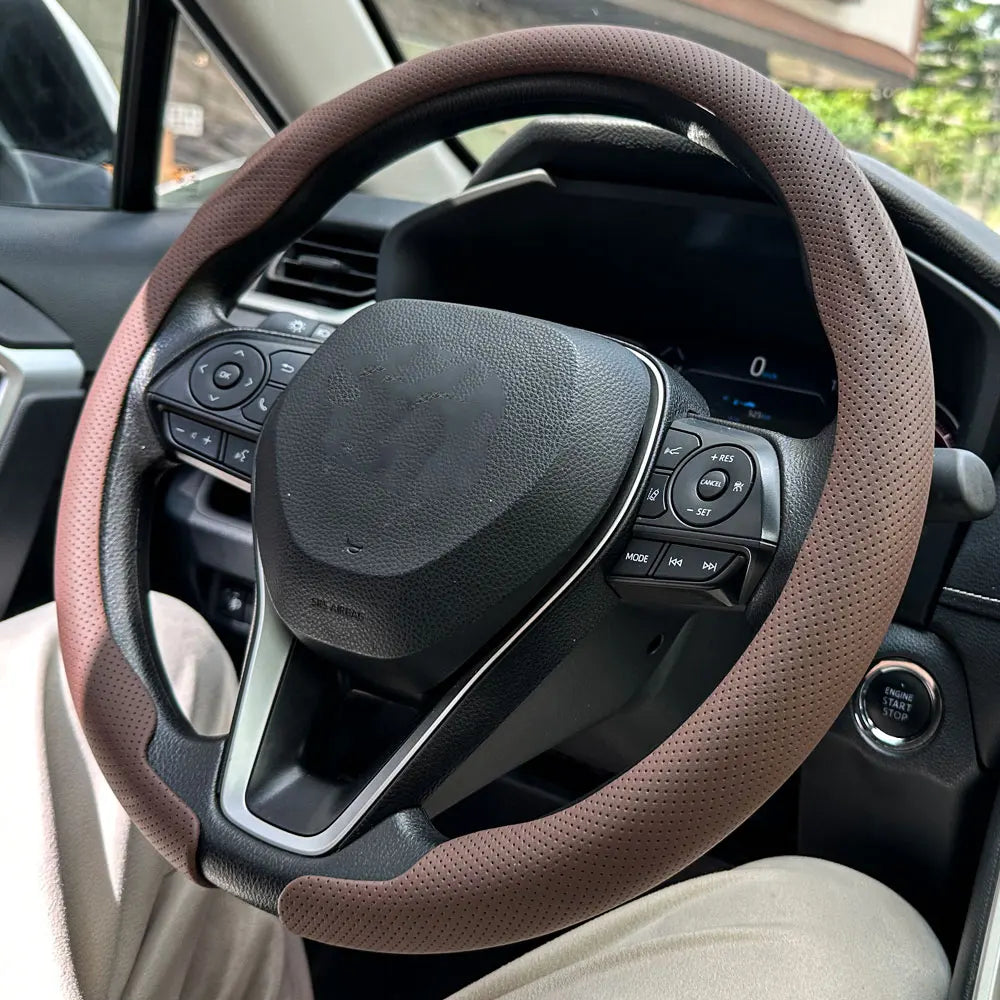 A close-up view of a brown leather steering wheel cover installed on a car's steering wheel.