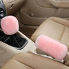 A set of plush pink car gear shift and handbrake covers inside a light tan car interior.