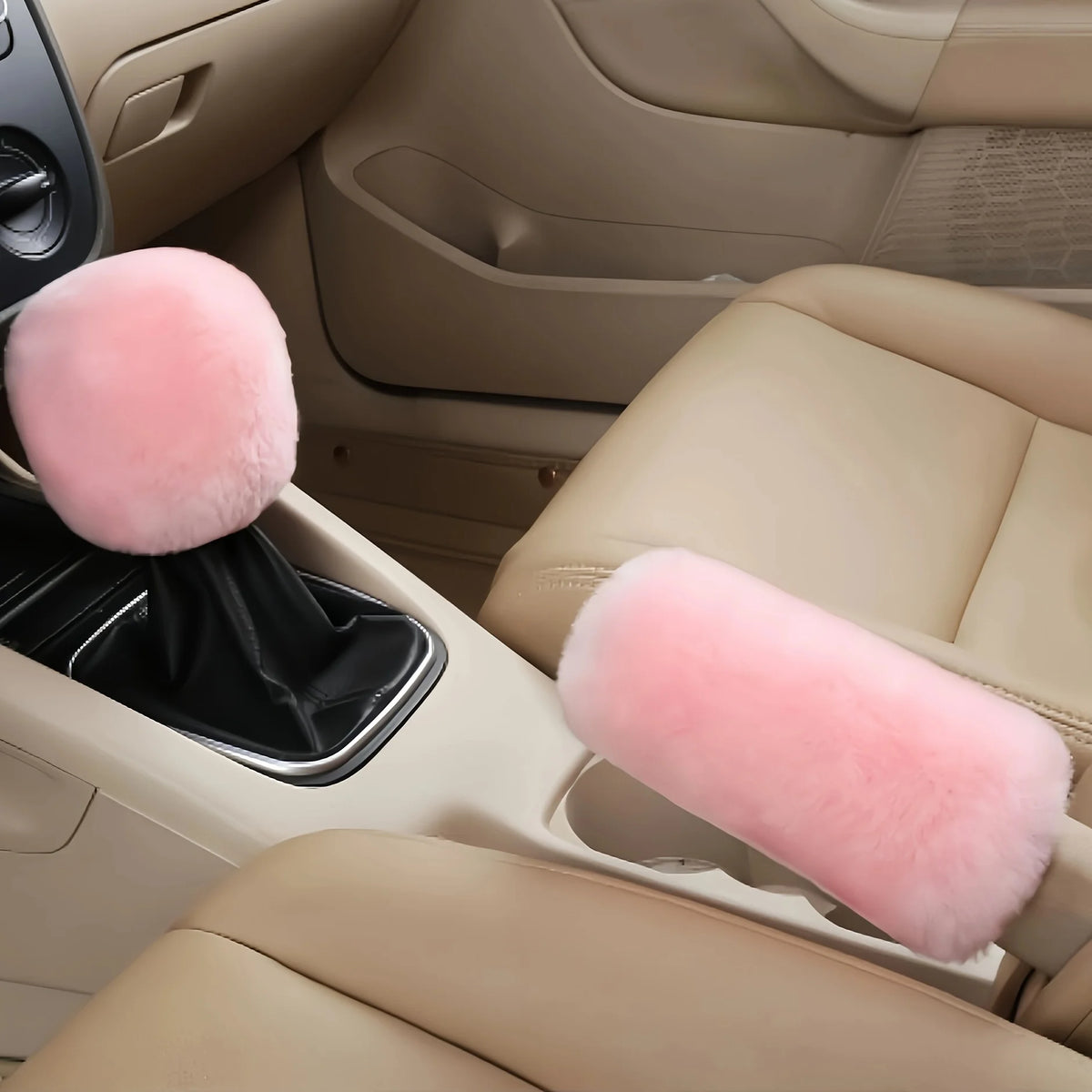 A set of plush pink car gear shift and handbrake covers inside a light tan car interior.