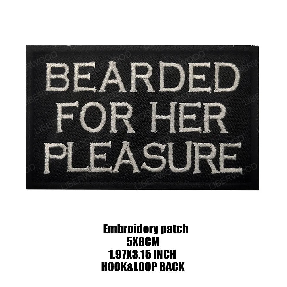 Black embroidered patch with white text that reads Bearded For Her Pleasure