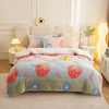 A pink and blue strawberry patterned plush throw blanket displayed on a beige sofa with white decorative pillows.
