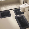 A set of black floor mats with the HOME logo placed on a bathroom floor next to a toilet.