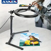A black foldable overhead tripod with a ring light is positioned above a smartphone for photography.