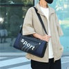 A person wearing a beige jacket is carrying a black and gray duffel bag.
