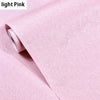 Roll of light pink embossed silk self-adhesive wallpaper being peeled from its roll.