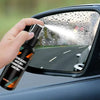 A hand sprays a car window with an anti fog hydrophobic coating spray.