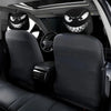 A set of two black car headrest covers featuring menacing devil faces, shown inside a vehicle.