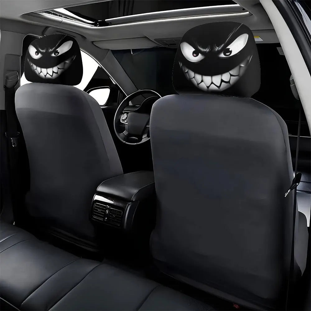 A set of two black car headrest covers featuring menacing devil faces, shown inside a vehicle.