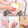 Hands are using reusable pink microfiber cleaning cloths to wash dishes in a kitchen sink.