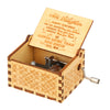 A vintage hand-cranked wooden music box with a lid open, featuring engraved text and a brass crank.