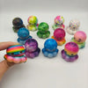 Collection de balles anti-stress et jouets anti-stress de Noël colorés, dans diverses nuances de vert, violet, rose et jaune.