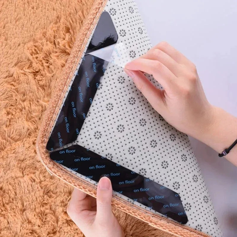 A hand is gripping a reusable non-slip rug gripper, which is black and white patterned, against a fluffy orange rug.