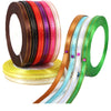 A collection of satin ribbons in various colors including brown, red, purple, orange, and green, displayed on a spool.
