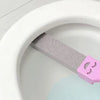 A pink pumice stone cleaning stick is shown inside a white toilet bowl.