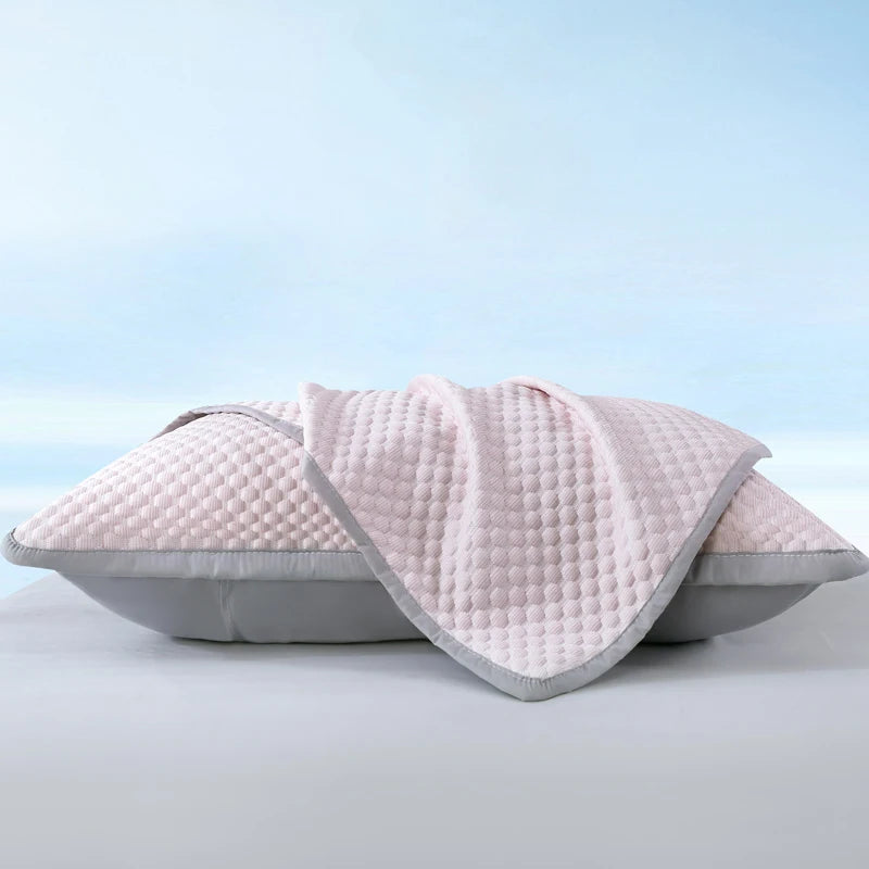 A light pink quilted breathable cooling pillowcase folded on a white surface.