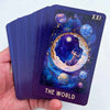 A purple tarot card showing a celestial scene with planets and stars, labeled XXI The World.