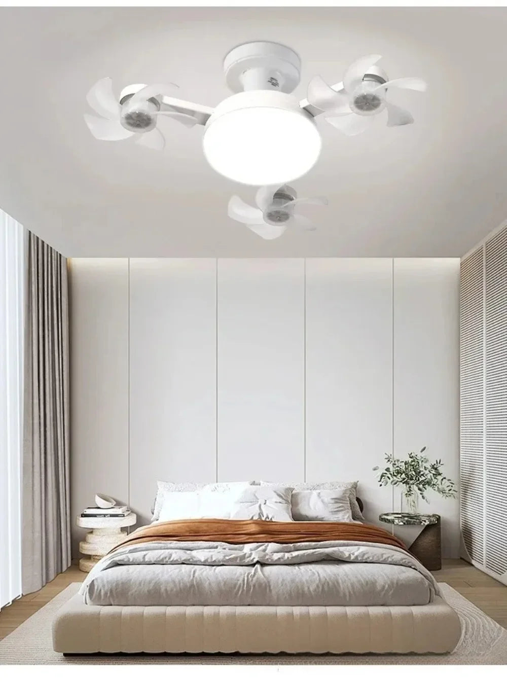 Modern white ceiling fan with multiple light heads and a large circular diffuser in a bedroom setting