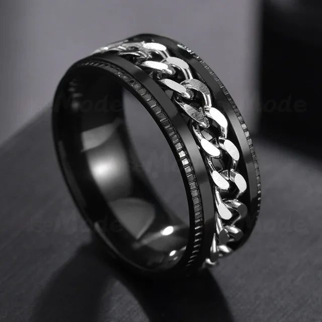A close-up shot of a black stainless steel spinner ring with a silver chain design.