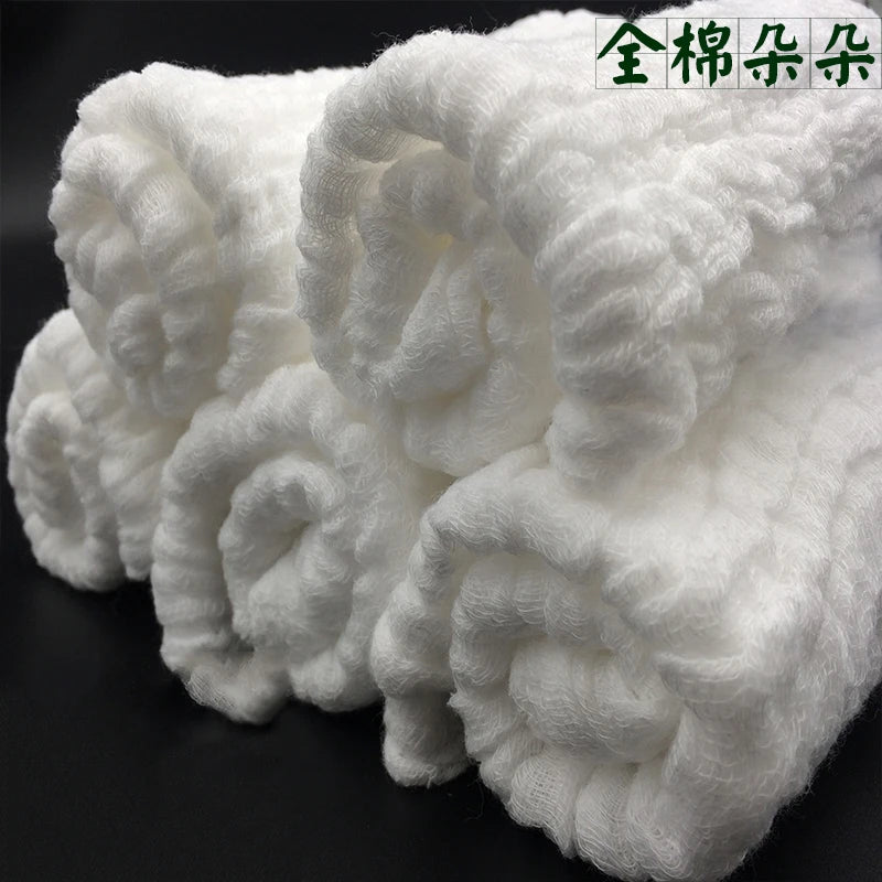 A stack of white, fluffy cotton muslin baby washcloths rolled into balls.