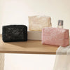 Three makeup bags in black, cream, and pink lace mesh fabric displayed on a wooden surface.