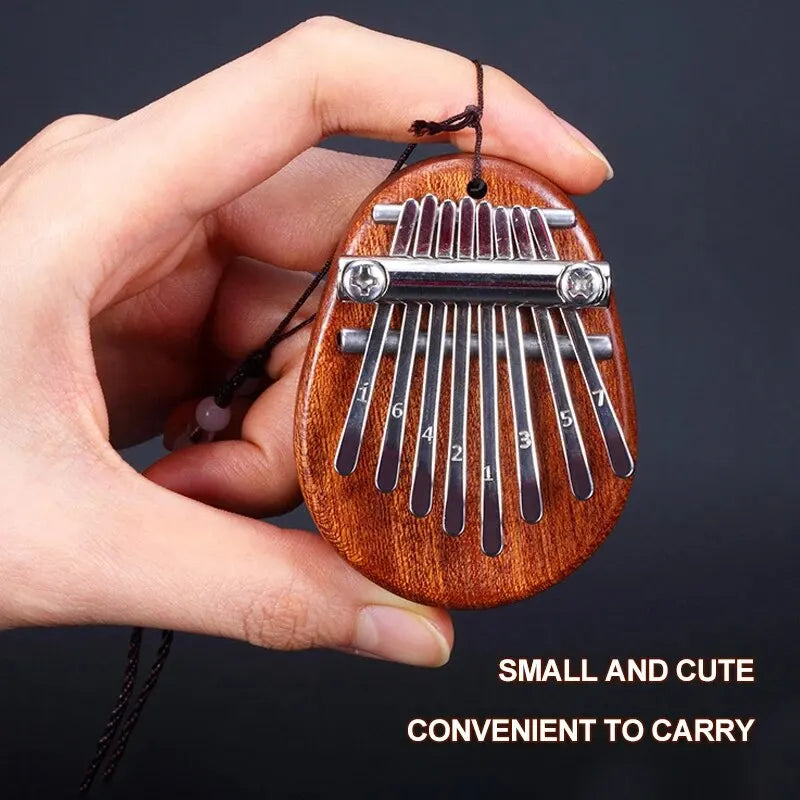 A hand holds a small wooden kalimba thumb piano with metal tines, designed to be convenient to carry.