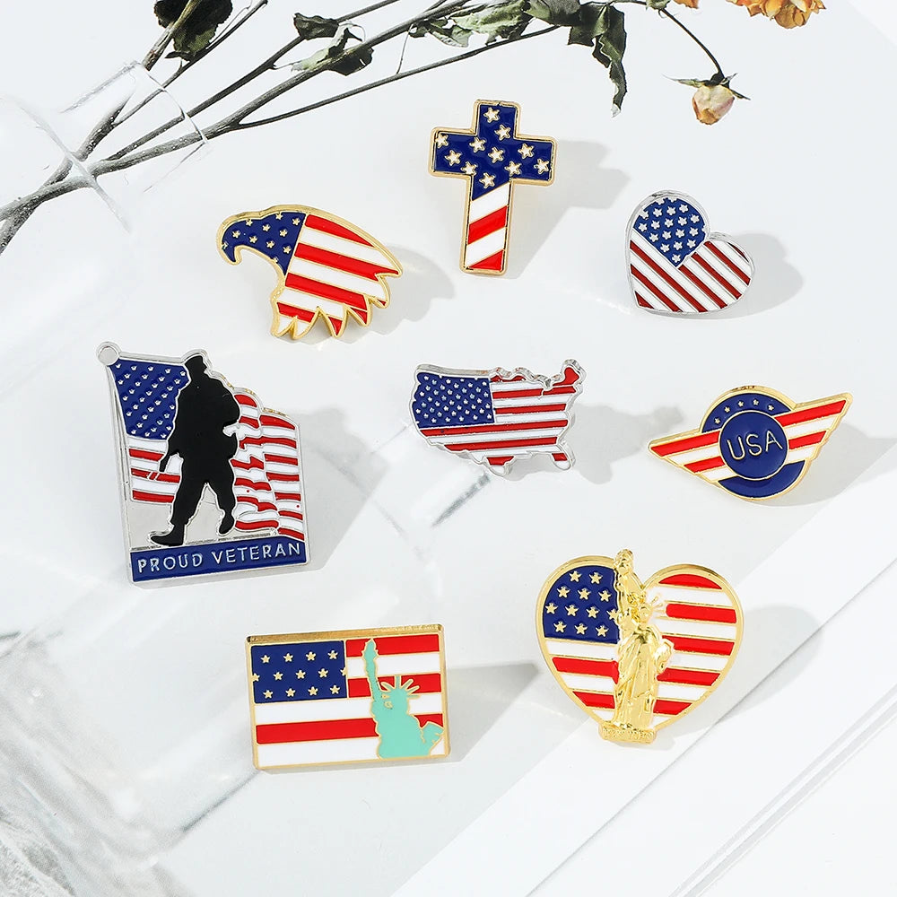 A collection of enamel pins featuring American flag designs, including a cross, a silhouette, and a flag outline.