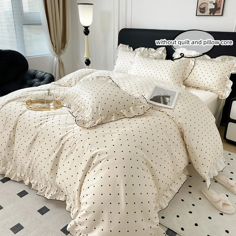 A beige duvet cover set with black polka dots displayed on a bed with a black headboard.