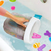 A hand is placing a white hanging bath toy storage bag with a mesh net into a tub filled with soapy water and colorful bath t