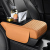 A tan leather car armrest cushion with storage and cup holders placed on a black car seat.