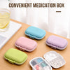 A collection of mini convenient medication boxes in various pastel colors and a clear compartment organizer are displayed on 