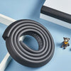 A roll of black soft NBR table edge and corner guard bumper strips lying on a light blue surface.