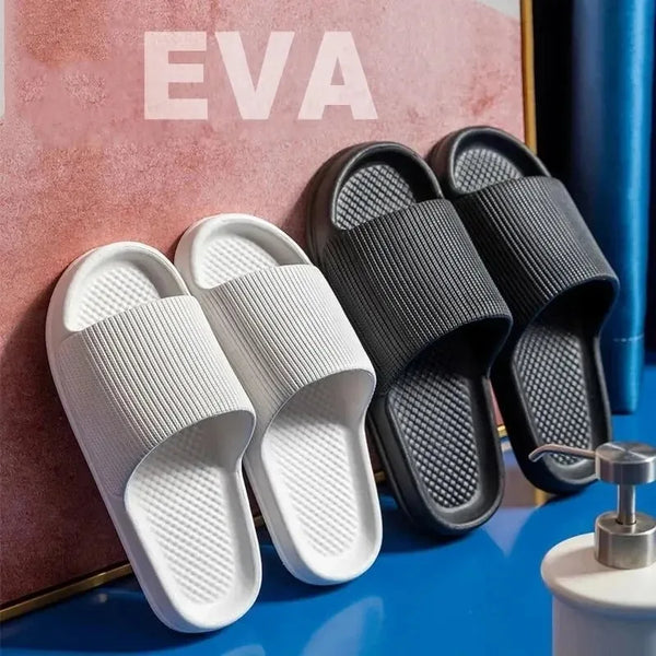 Un par de pantuflas para la ducha EVA negras y blancas antideslizantes sobre una superficie azul.