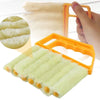 An orange dusting brush with soft green bristles is shown being used to clean blinds or crevices.