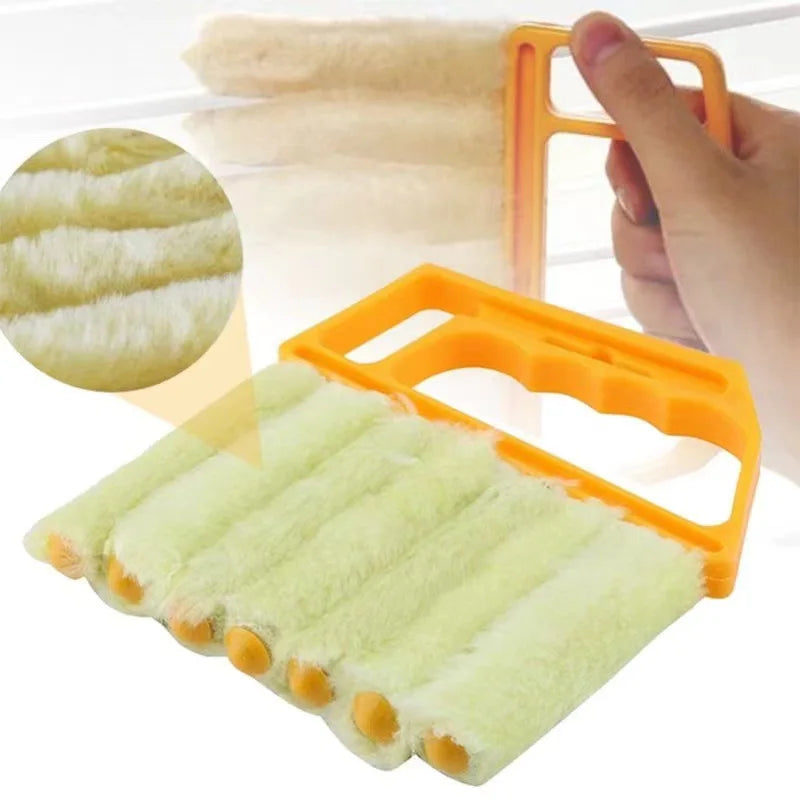 An orange dusting brush with soft green bristles is shown being used to clean blinds or crevices.