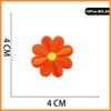 Orange embroidered iron-on patch shaped like a flower or rose with a yellow center