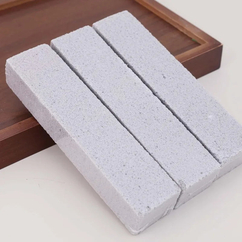 Three white pumice stone cleaning sticks resting on a wooden tray.