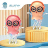 A pink Jellyfish toy with large glasses and headphones is shown standing on a yellow circular base.