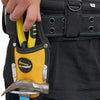 A hand is holding a yellow heavy-duty pliers tool with a hammer loop inside a black leather holster attached to a work belt.