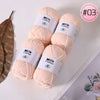 A pile of pink Milk Cotton yarn balls is displayed on a white surface with a brown leaf and a pink circular label.