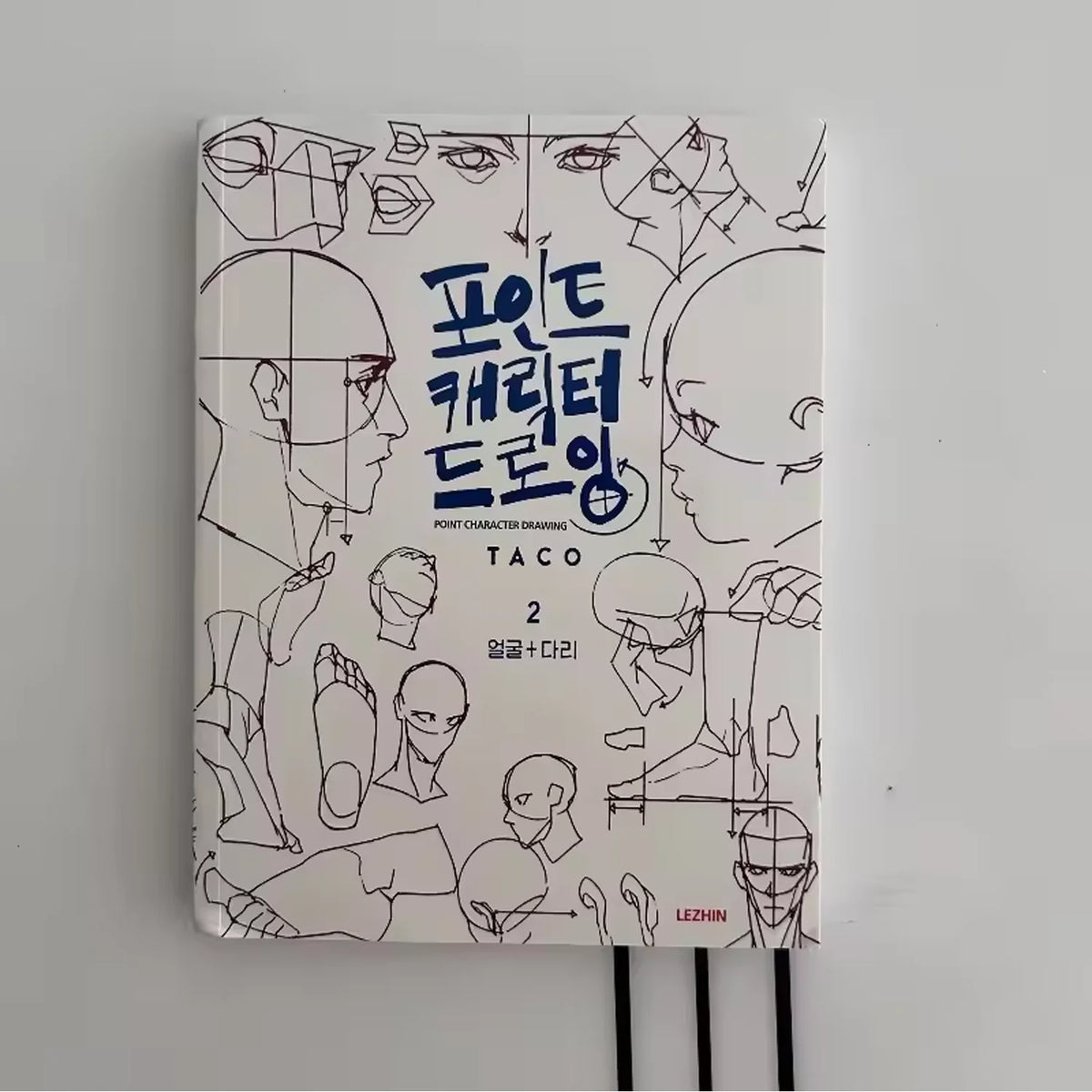 A book titled Point Character Drawing featuring line art of various faces and figures in Korean and English.