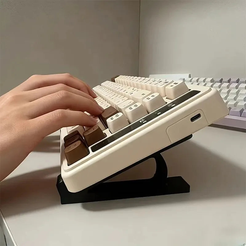 A hand is placing a white ergonomic keyboard riser with brown keycaps onto a black non-slip base.
