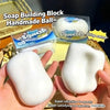 A hand holds a white squishy building block ball next to its packaging and a squeeze toy.